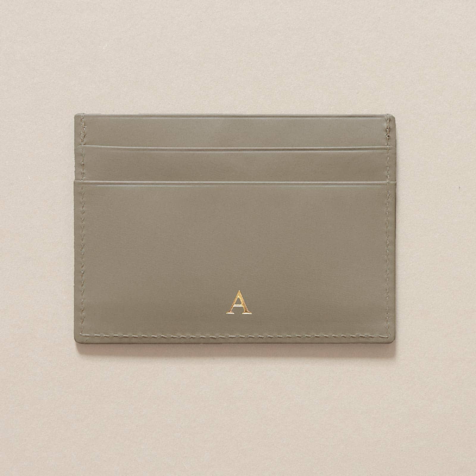 Cardholder aus Leder in Moosgrau mit Beispiel für eine Personalisierung in Form einer Goldprägung mit einem Buchstaben