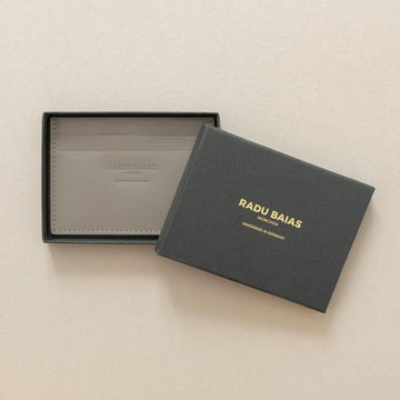 Cardholder aus Leder in Moosgrau mit Logoprägung in einer schwarzen Geschenkschachtel mit Radu Baias Logo liegend