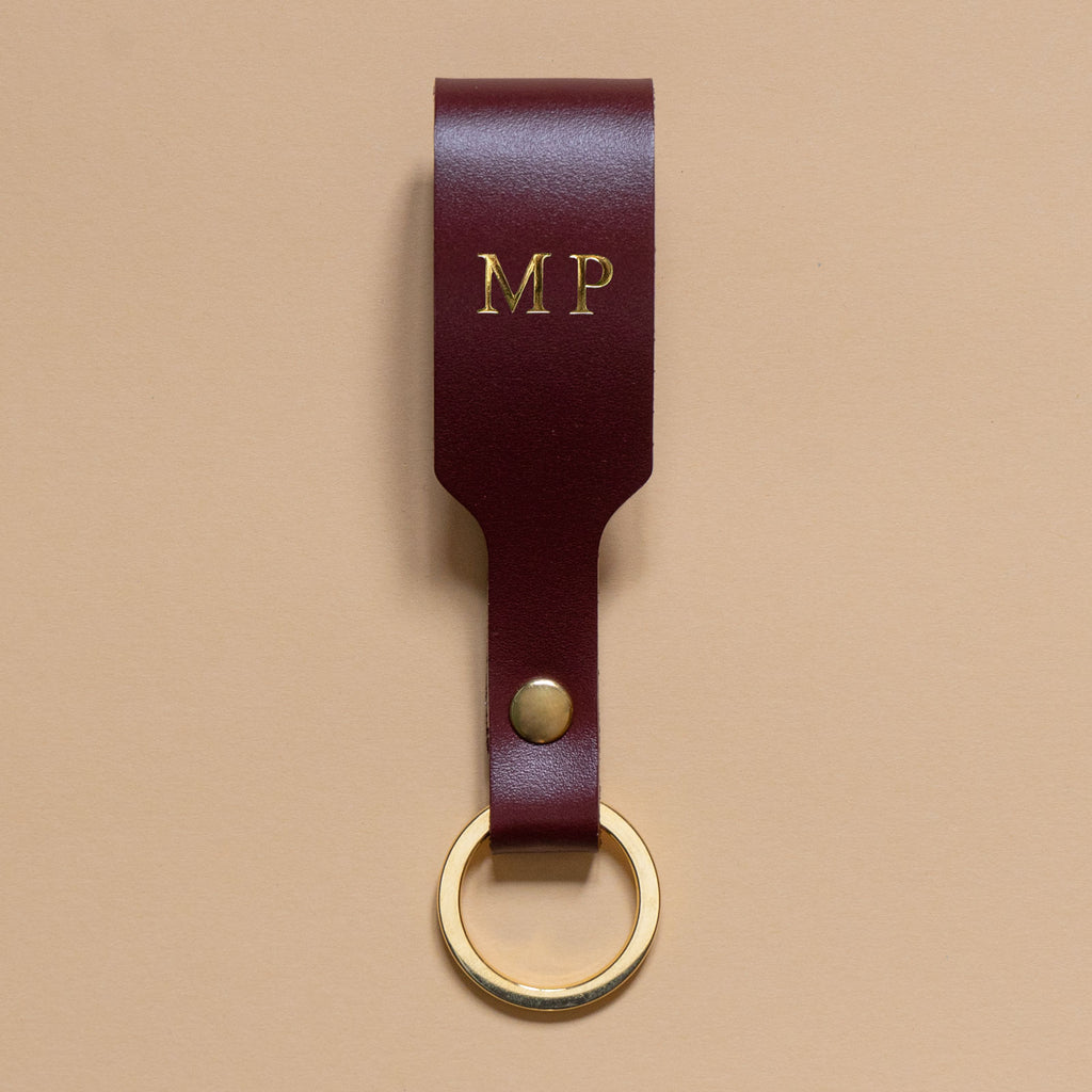 Schlüsselanhänger mit bordeauxroter Lederschlaufe und goldenem Ring aus Edelstahln und goldener Prägung