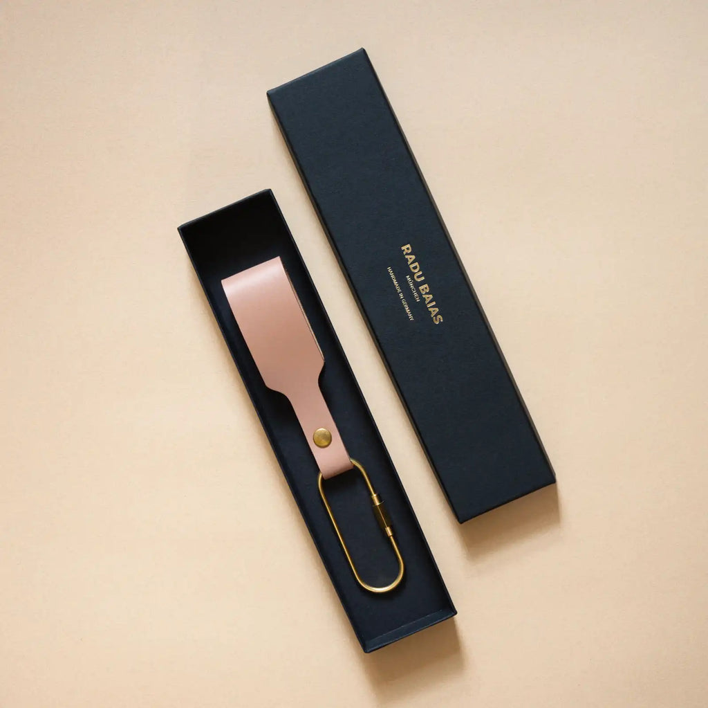 Puderfarbener Schlüsselanhänger mit Lederschlaufe und goldenem Messing-Karabiner verpackt in einer schwarzen eleganten Geschenkschachtel