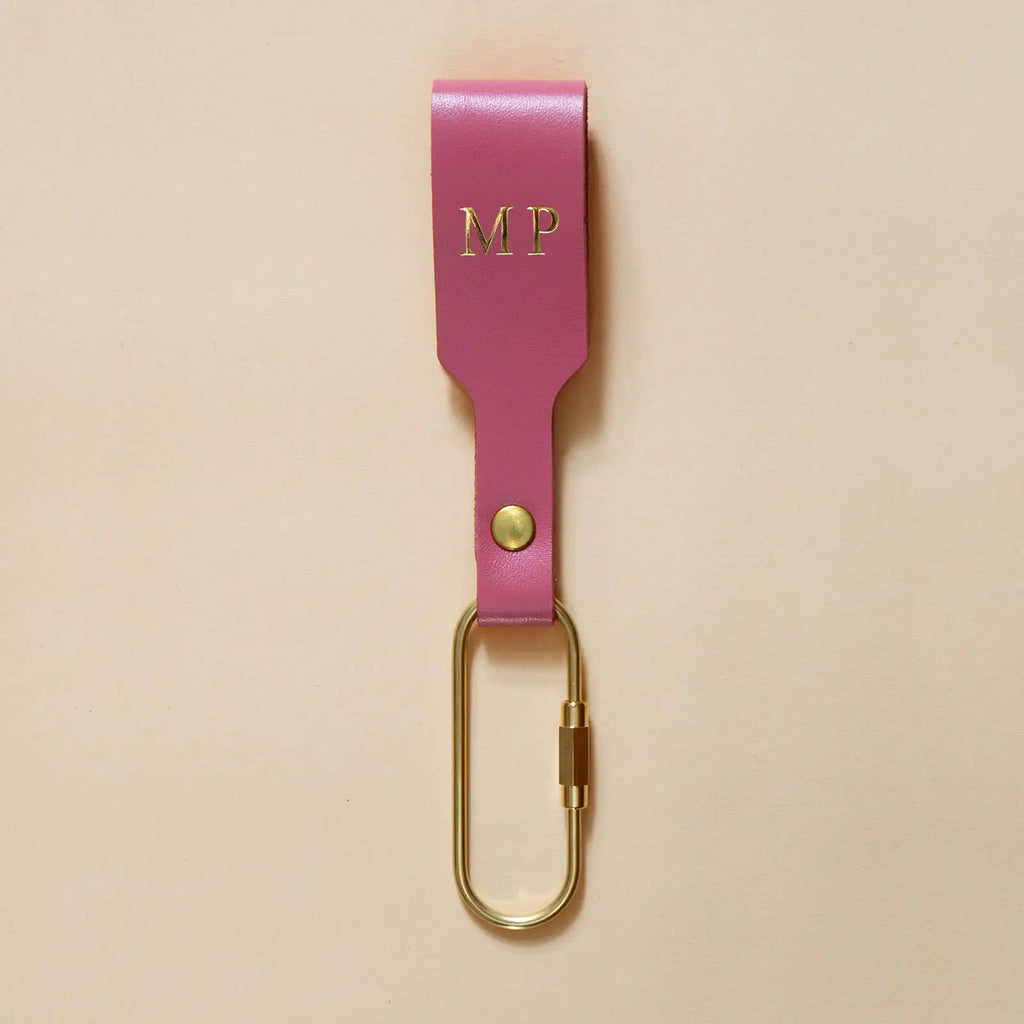 Rosafarbener Schlüsselanhänger mit Lederschlaufe und goldenem Karabiner und goldener Prägung