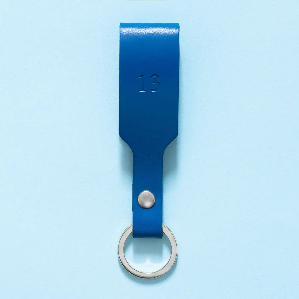 Schlüsselanhänger mit blauer Lederschlaufe, silbernem Schlüsselring und silberner Personalisierung in Form einer Blindprägung mit Zahl 