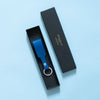 Blauer Schlüsselanhänger mit Lederschlaufe und silbernem Schlüsselring verpackt in einer eleganten schwarzen Geschenkschachtel