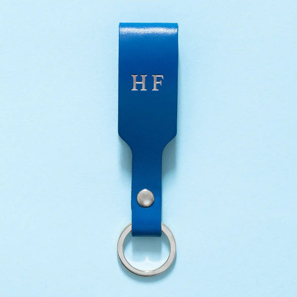 Schlüsselanhänger mit blauer Lederschlaufe, silbernem Schlüsselring und silberner Personalisierung in Form einer Prägung mit Initialen