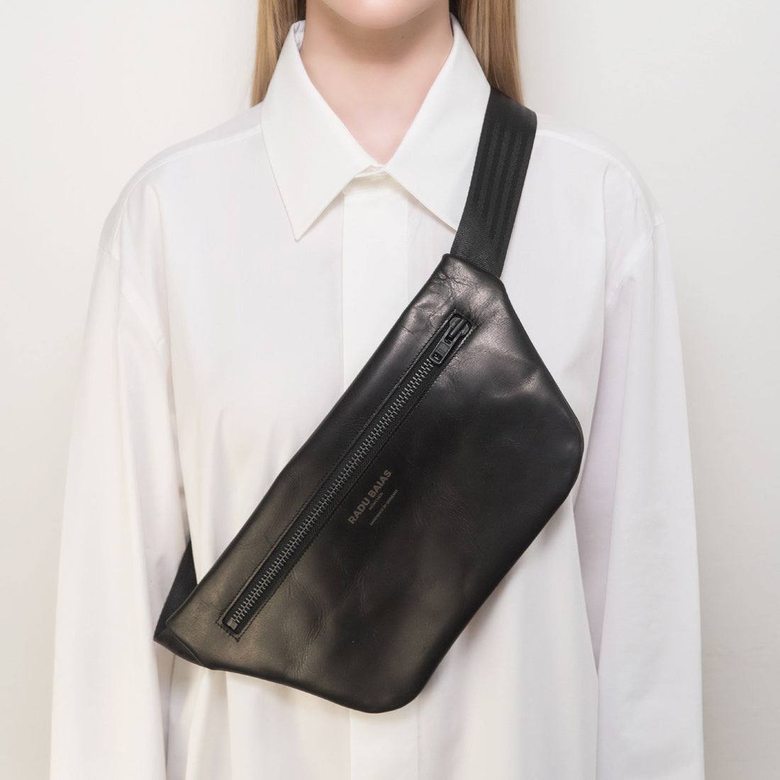 Vorderansicht einer schwarzen Crossbody Tasche aus pflanzlich gegerbtem Leder mit schwarzem Reißverschluss und schwarzem Tragegurt