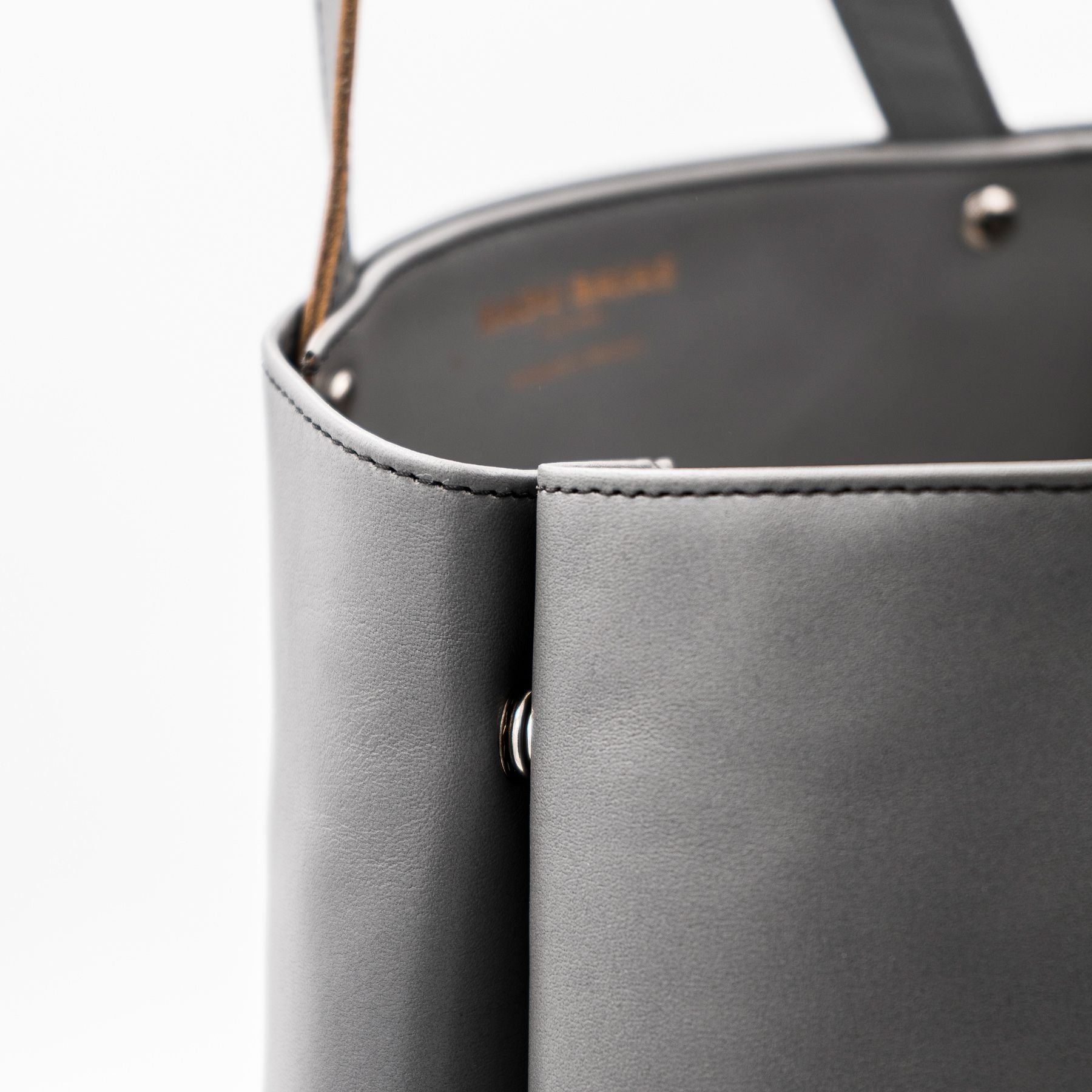 Seitliche Detailansicht eines grauen Shoppers aus pflanzlich gegerbtem Olivenleder® mit matter Oberfläche und silbernen Beschlägen