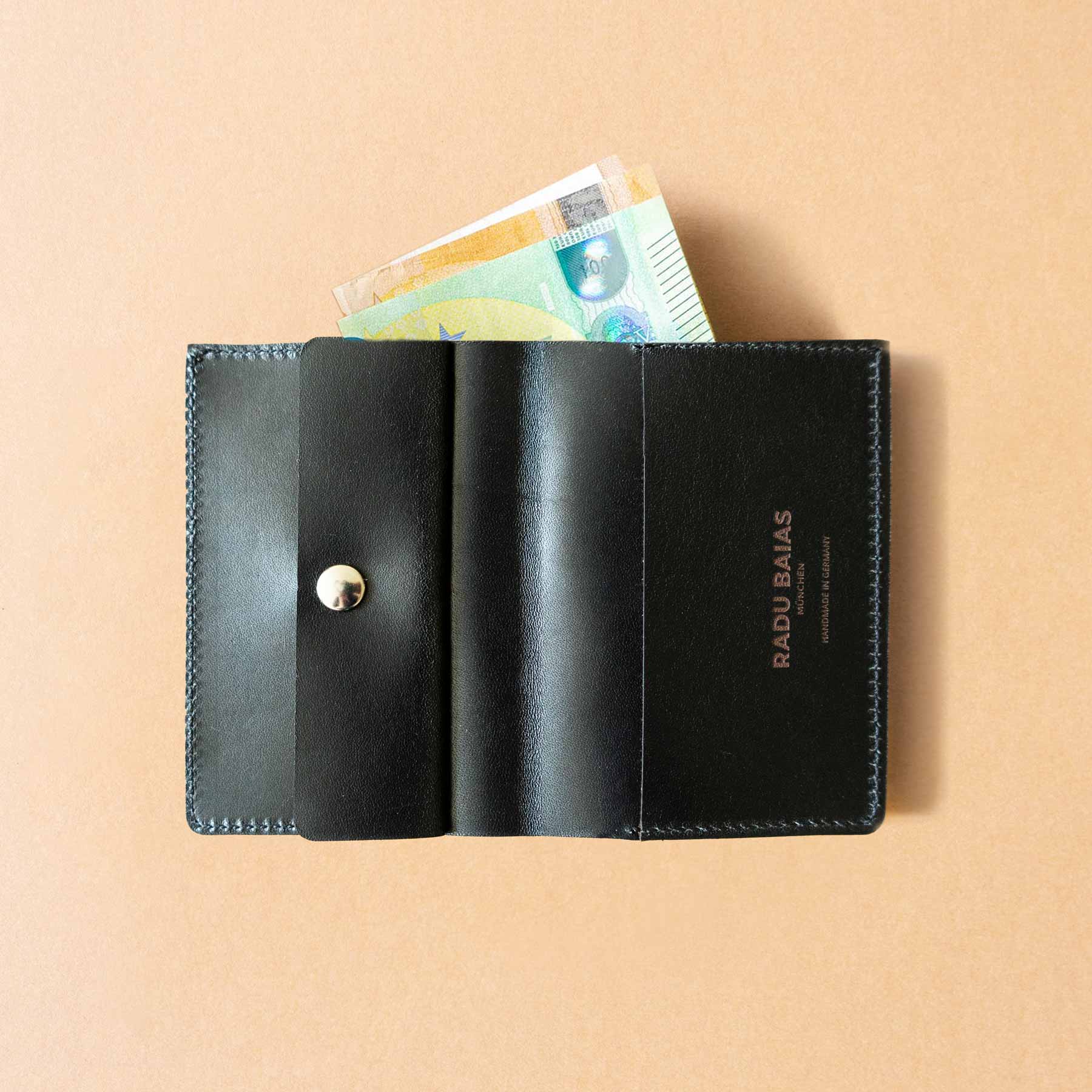 Aufgeklappte Ansicht des Slim Portemonnaies mit Scheinen und Münzfach aus pflanzlich gegerbtem Leder